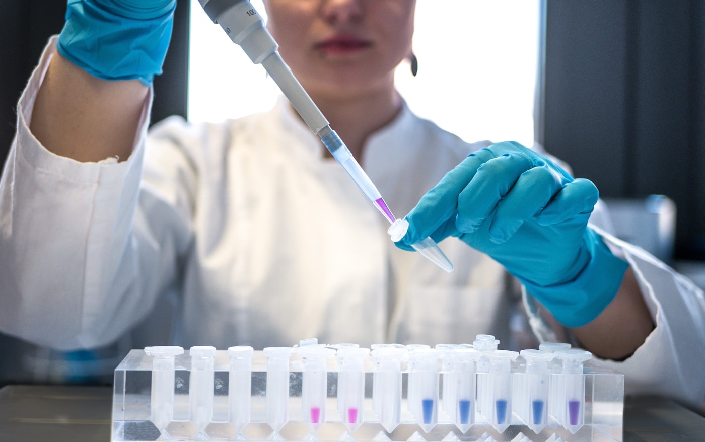 A researcher pipetting samples into tubes at a laboratory bench